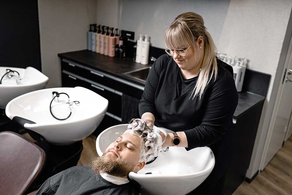 hiustenpesu Kampaaja pesee mies-asiakkaan hiuksia